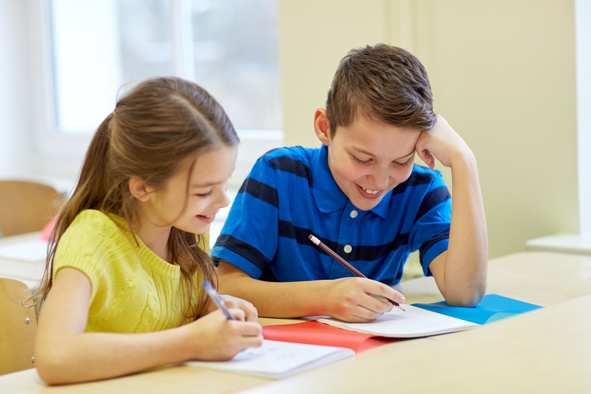 group of school kids writing test in classroom