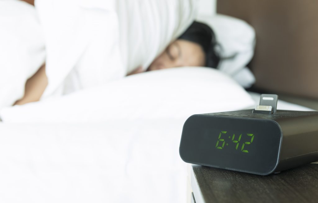 A Woman Sleeping Beside a Digital Alarm Clock